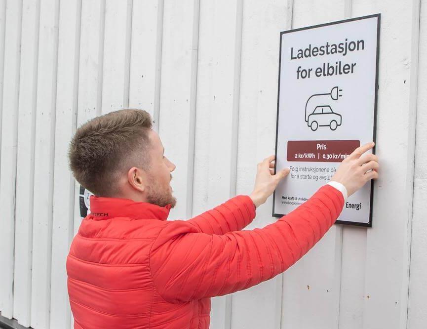Erling Aalvik henger opp skiltet som forteller gjestene at n&aring; kan du lade bilen din p&aring; Kjerring&oslash;y Bryggehotell