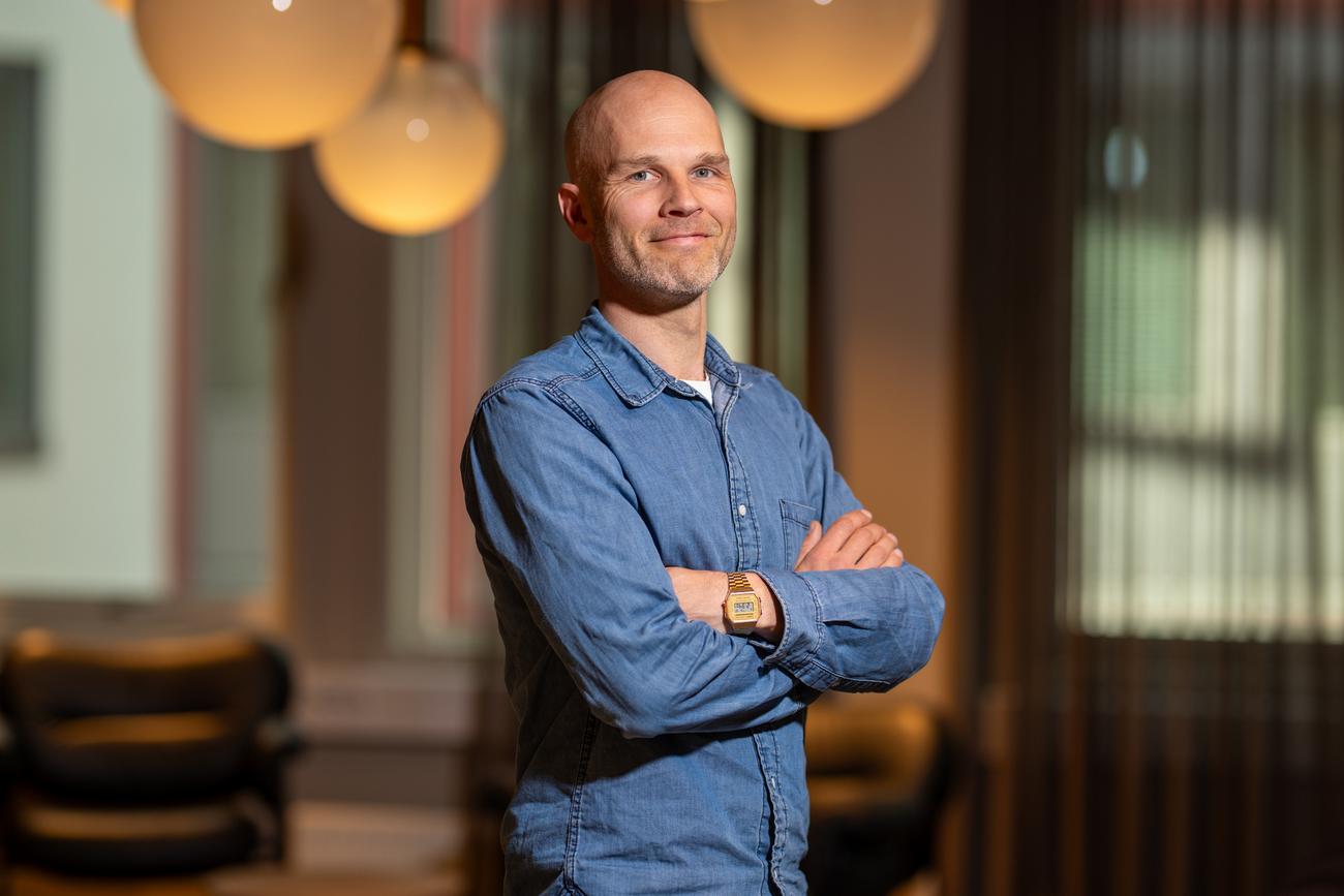 Pontus Hed&eacute;n i bl&aring; dongeriskjorte st&aring;r med armene i kors innend&oslash;rs, med runde taklamper i bakgrunnen